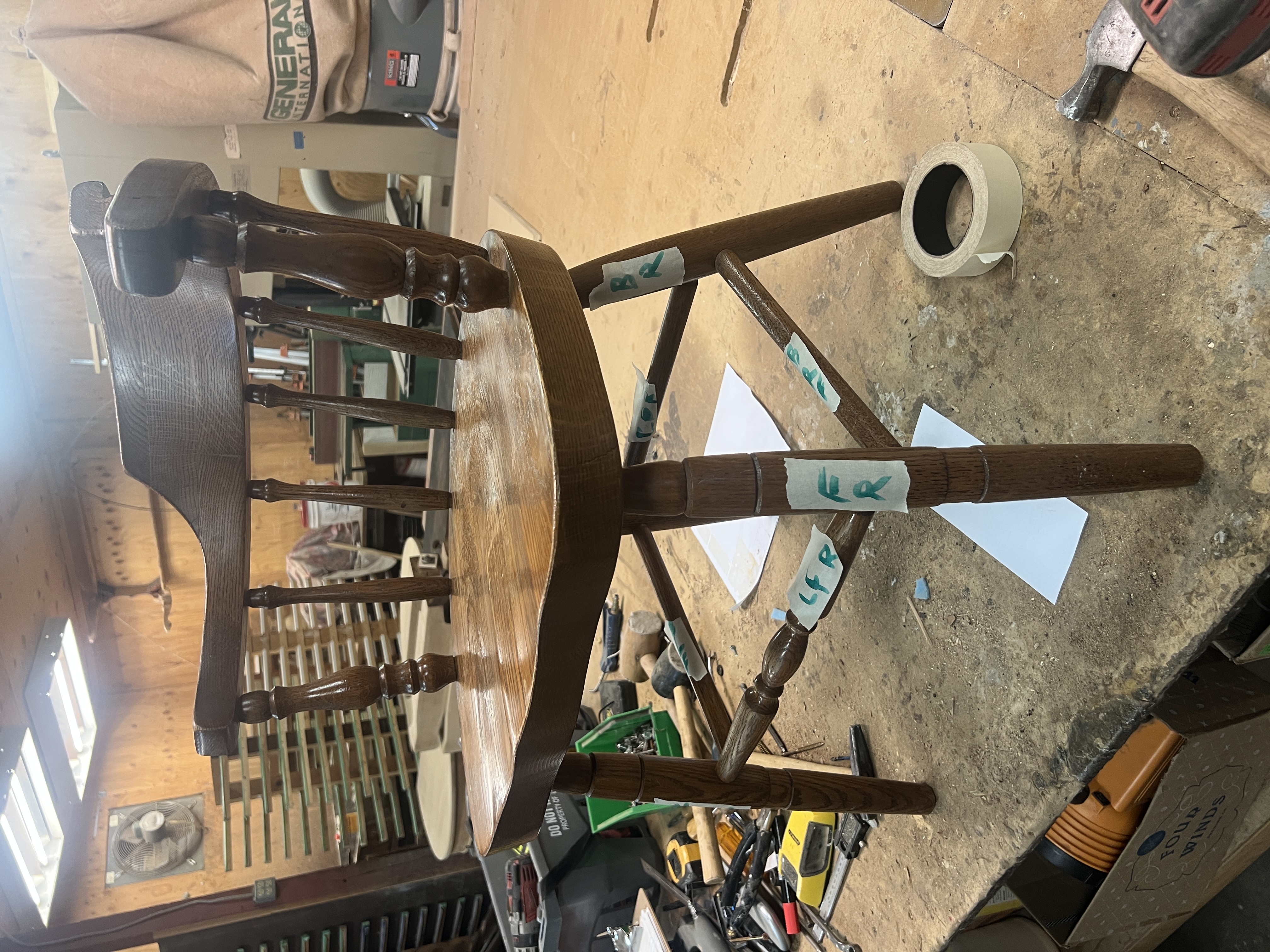 A brown wooden chair with spindle backs and curved armrest before the refinishing