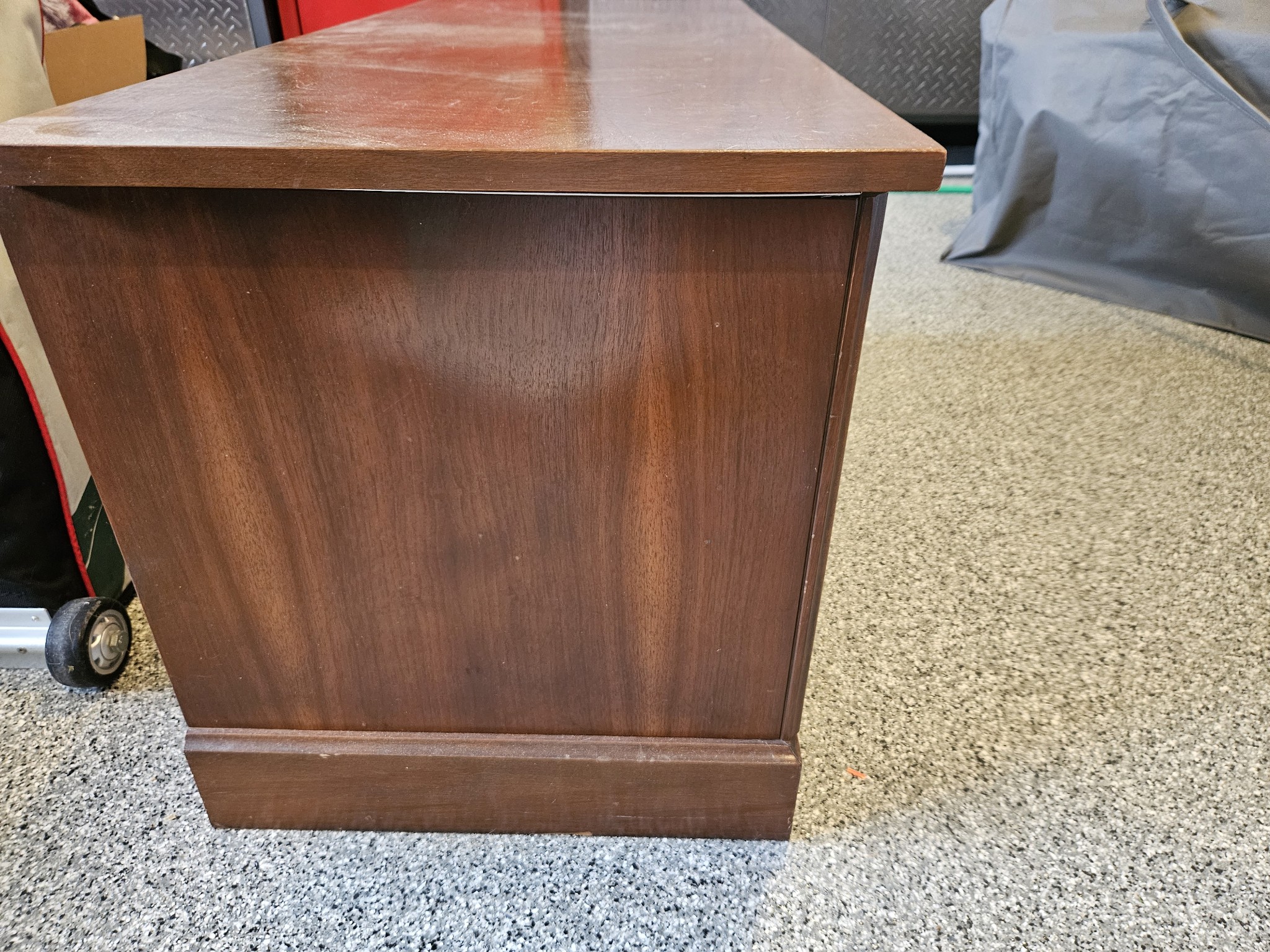 Side view of a vintage dark walnut sideboard with four paneled doors and brass ring handles.
