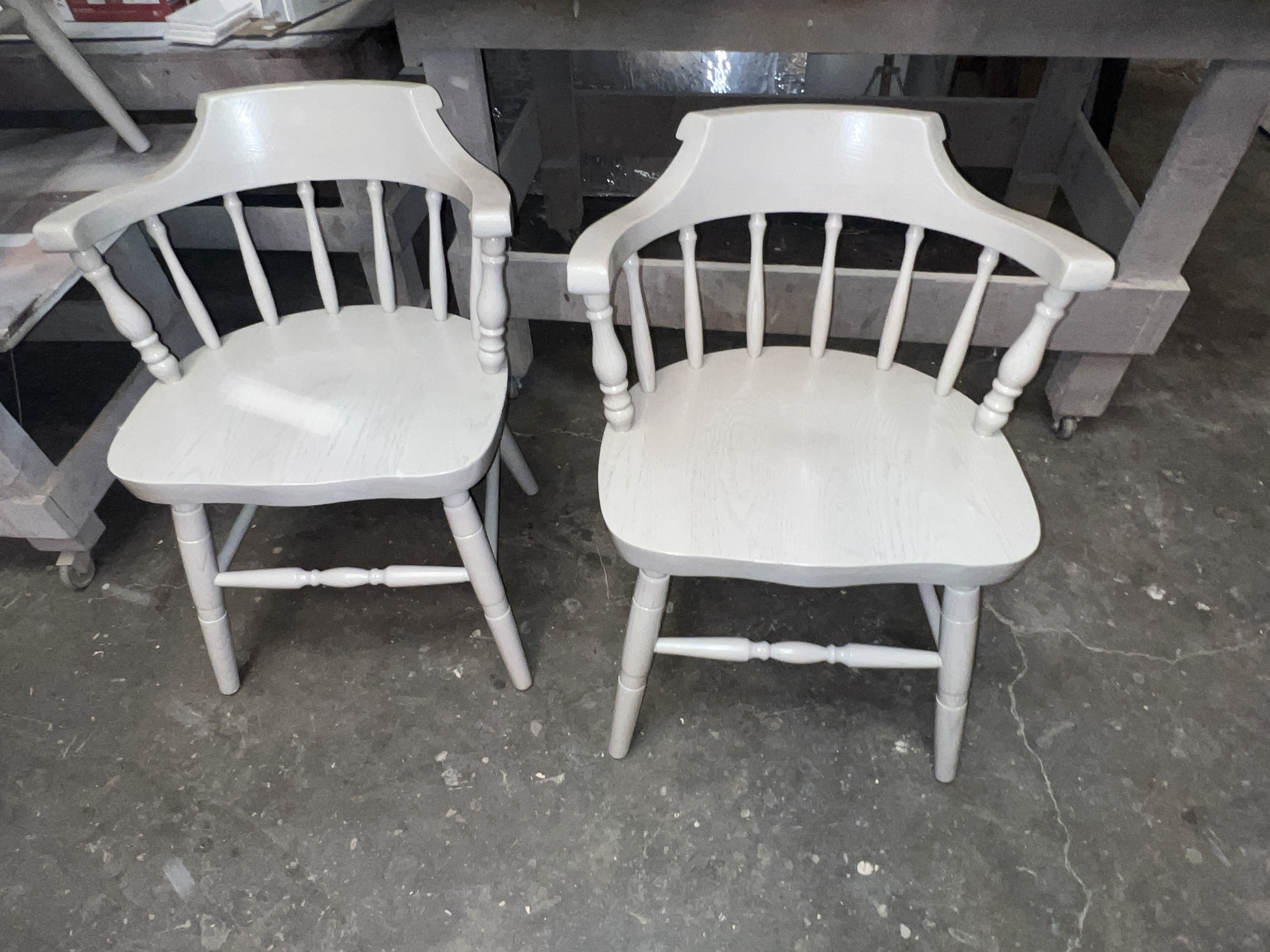 2 white wooden chairs with spindle backs and curved armrests