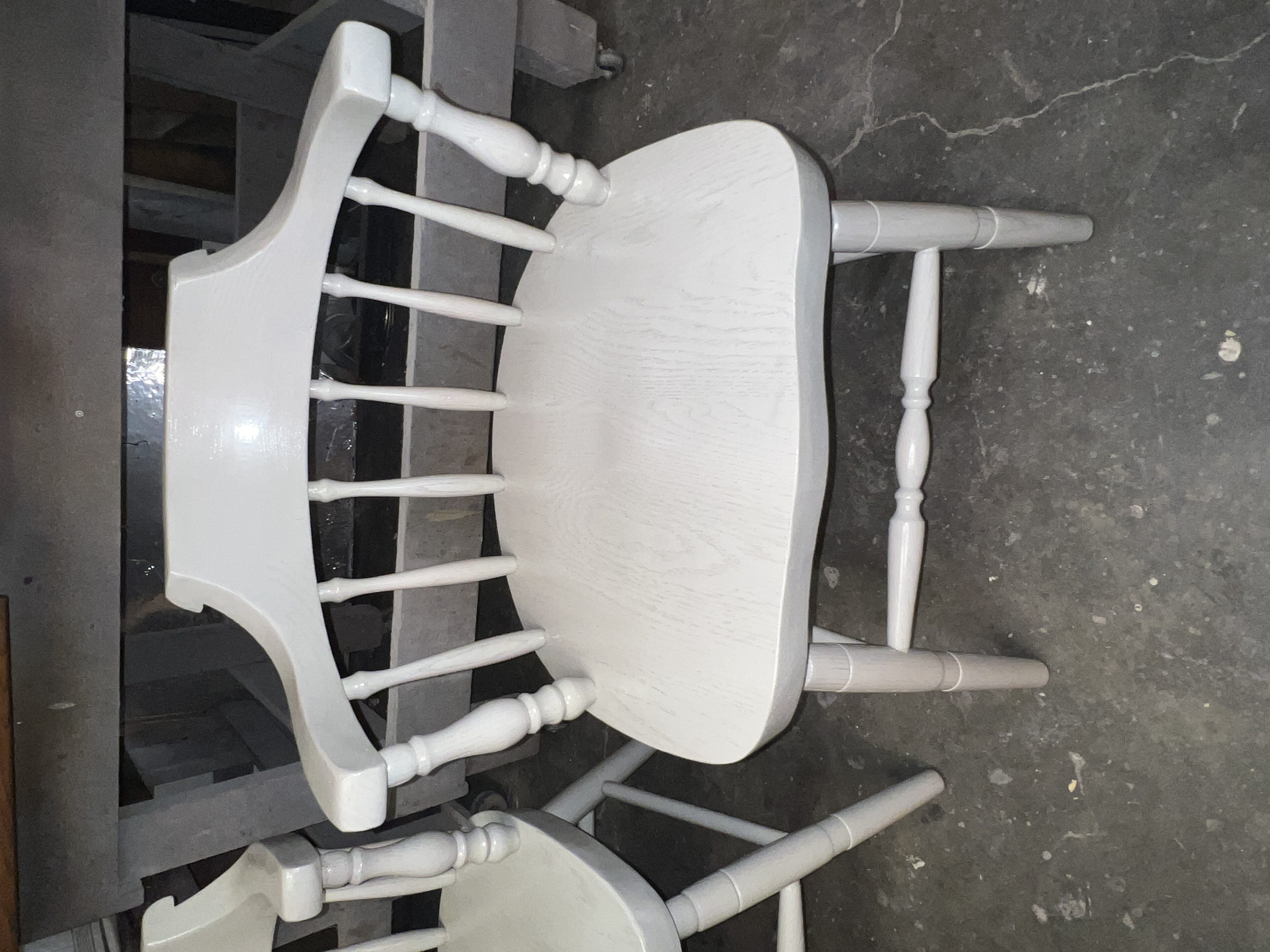 White wooden chair with spindle backs and curved armrest