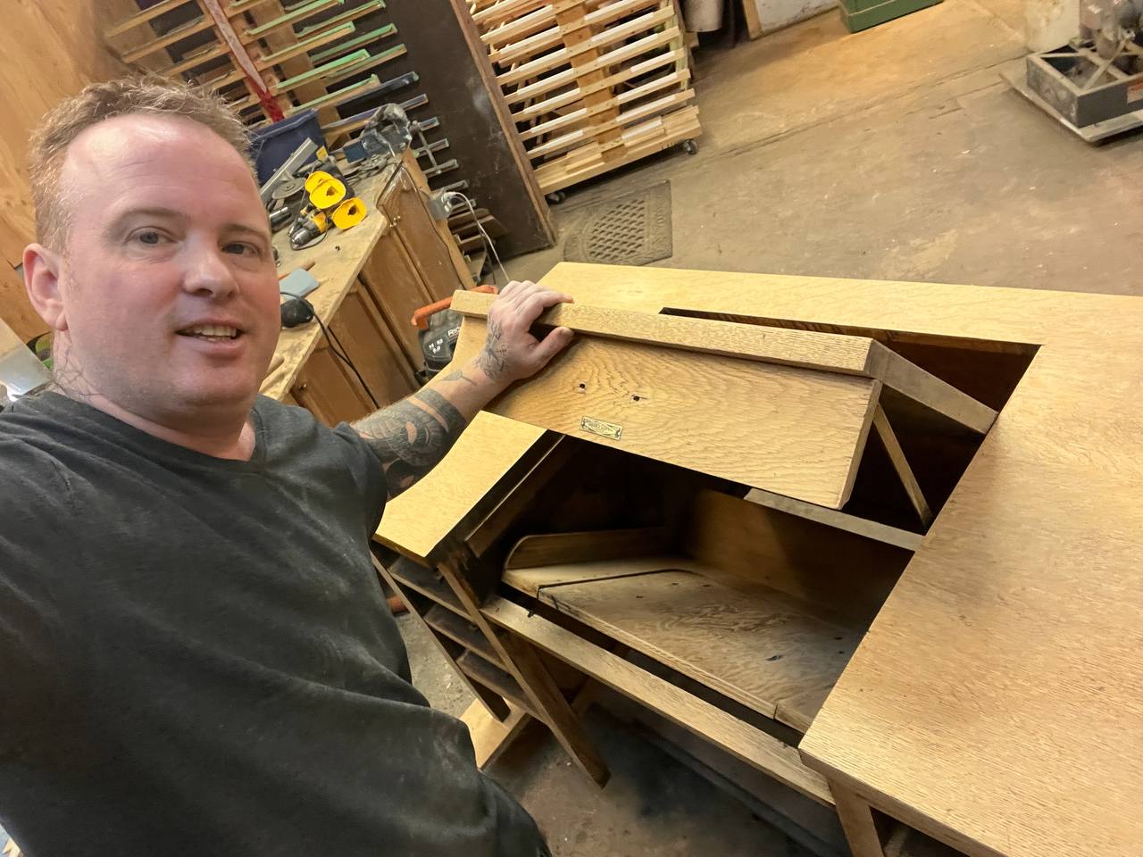 A person working on a light brown wooden desk with an open compartment.