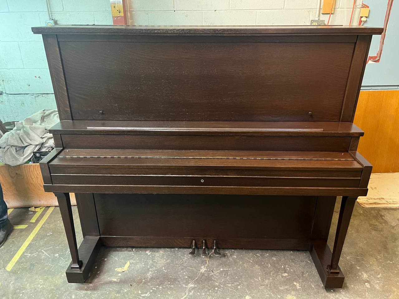 An upright piano refinished in a dark brown color
