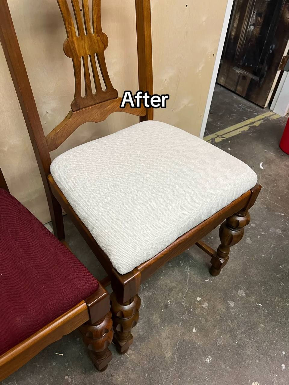 A wooden dining chair with a medium to dark-toned hardwood frame, featuring turned legs and a vertical slat backrest with a curved top rail, upholstered in white-colored fabric
