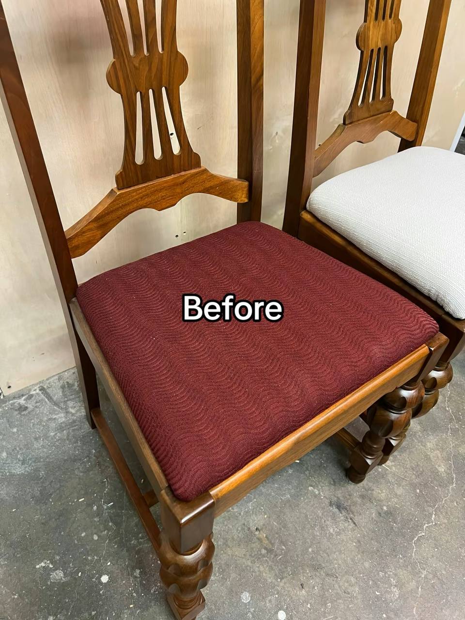 A wooden dining chair with a medium to dark-toned hardwood frame, featuring turned legs and a vertical slat backrest with a curved top rail, in a maroon-colored fabric