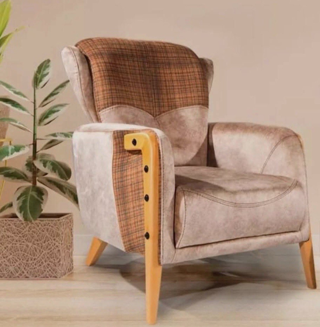 Modern wingback armchair with beige leatherette and brown plaid fabric upholstery, featuring curved wooden arms and tapered legs in natural finish.