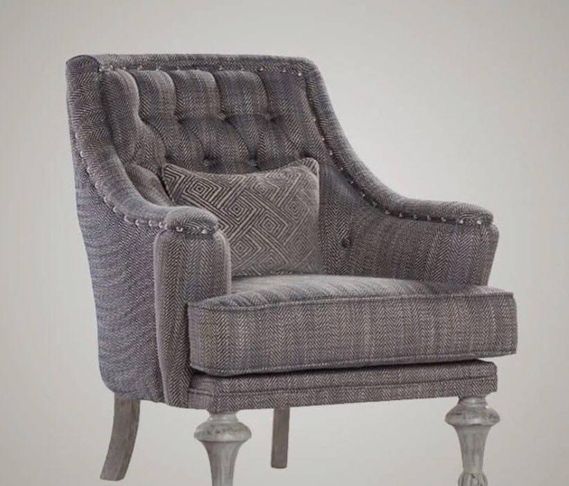 A gray armchair with a tufted backrest, herringbone-patterned fabric, and decorative metallic studs along the arms.