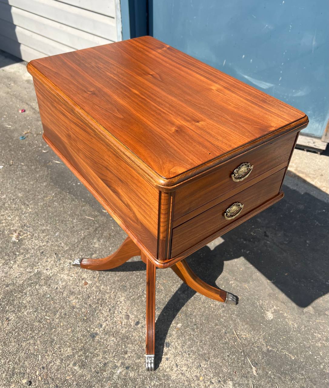 Refinished wooden side table with a rich walnut finish, two brass-accented drawers, and curved pedestal legs featuring metal foot caps