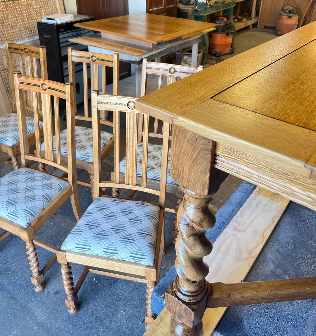 Refinished wooden dining table with carved legs and 6 dining chairs featuring light wood frames and reupholstered patterned fabric seats