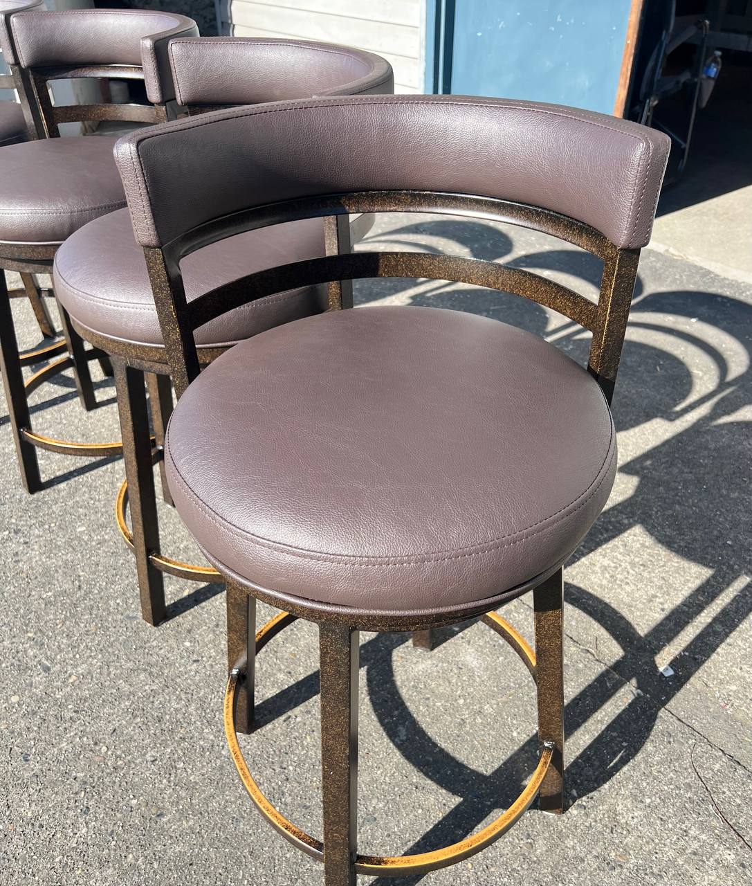 Brown leather-like upholstered bar stool with a curved backrest and metal legs in a contemporary design