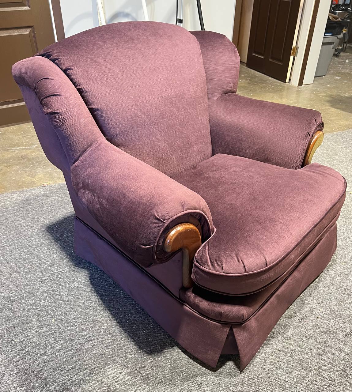 Plush rolled-arm armchair upholstered in solid plum fabric with wooden trim accents.