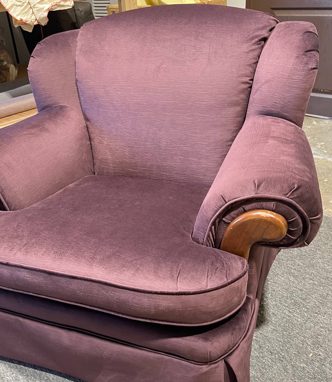 Plush rolled-arm armchair upholstered in solid plum fabric with wooden trim accents.