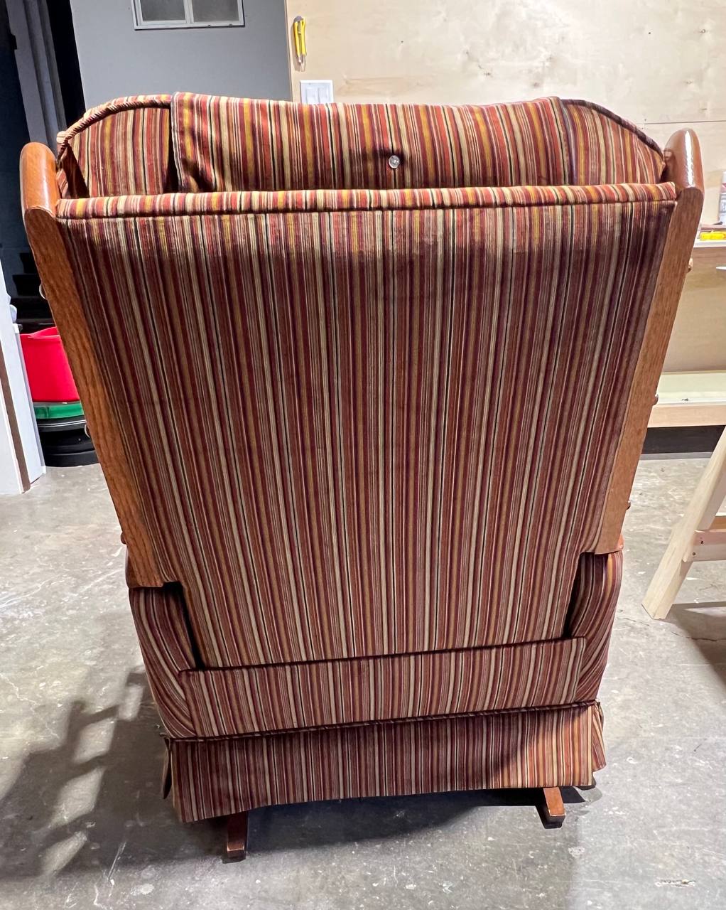 Back of vintage tufted wooden armchair with vertical striped fabric in earthy tones