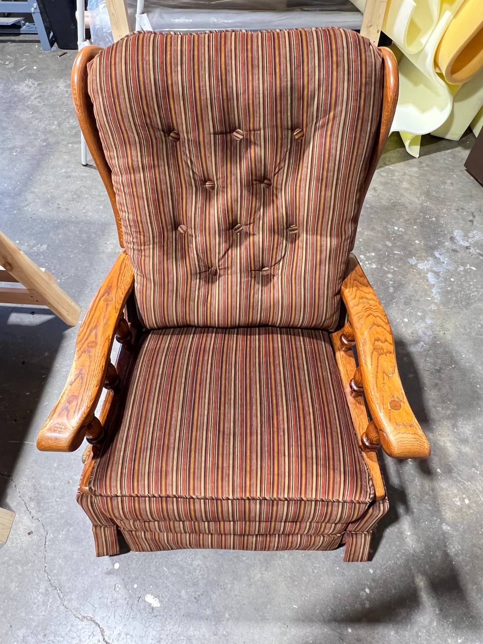 Vintage upholstered wooden armchair with vertical striped fabric in earthy tones and tufted backrest