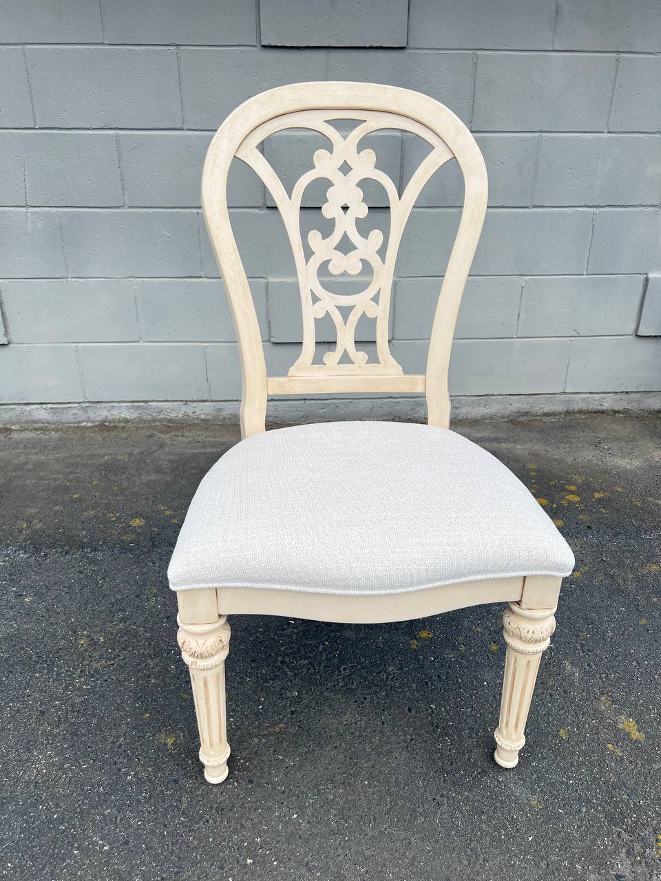 French Provincial-inspired dining chair with a cream ornate carved backrest and white upholstered seat