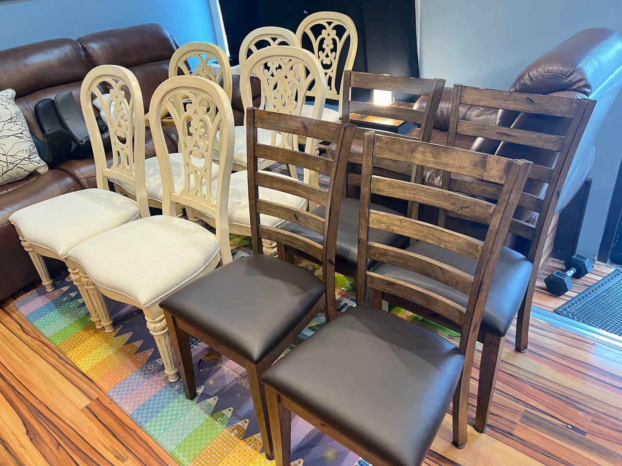 2 sets of dining chairs with 6 white seats and cream ornate carved backrests featuring a decorative curved pattern, and 4  brown ladder-back dining chairs.