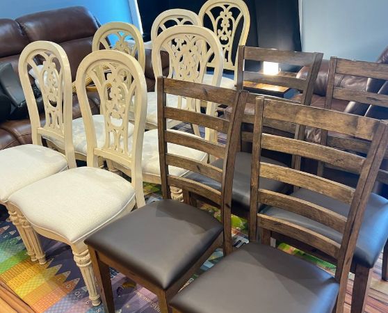2 sets of dining chairs with 6 white seats and cream ornate carved backrests featuring a decorative curved pattern, and 4 brown ladder-back dining chairs.