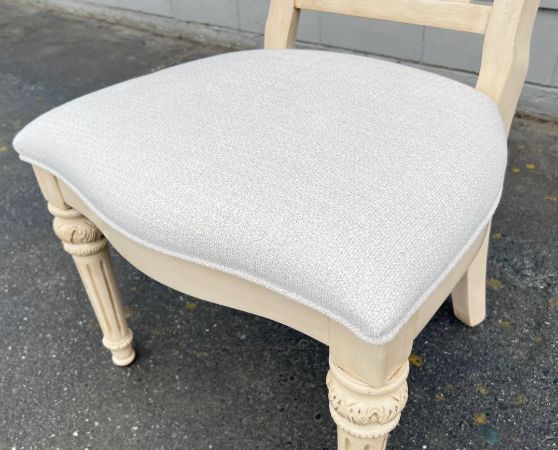 French Provincial-inspired dining chair with a cream ornate carved backrest and white upholstered seat