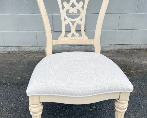 French Provincial-inspired dining chair with a cream ornate carved backrest and white upholstered seat