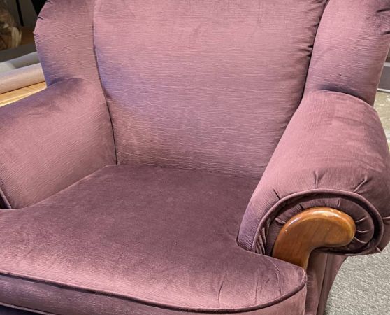 Plush rolled-arm armchair upholstered in solid plum fabric with wooden trim accents.