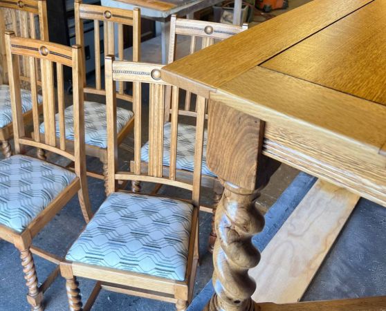 Refinished wooden dining table with carved legs and 6 dining chairs featuring light wood frames and reupholstered patterned fabric seats