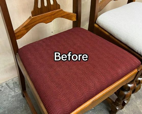 A wooden dining chair with a medium to dark-toned hardwood frame, featuring turned legs and a vertical slat backrest with a curved top rail, in a maroon-colored fabric