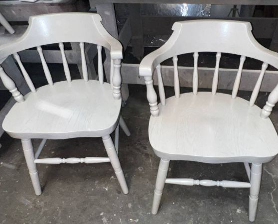 2 white wooden chairs with spindle backs and curved armrests