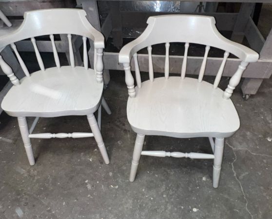 2 white wooden chairs with spindle backs and curved armrests