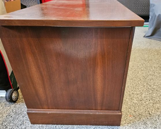 Side view of a vintage dark walnut sideboard with four paneled doors and brass ring handles.
