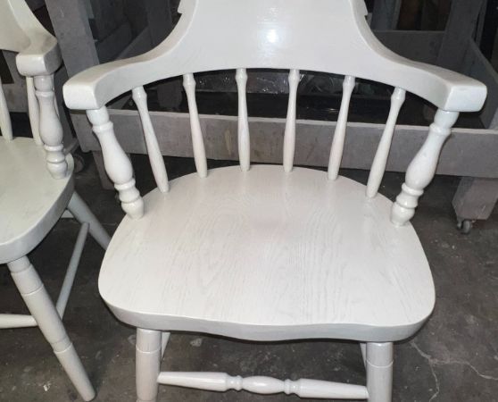 White wooden chair with spindle backs and curved armrest
