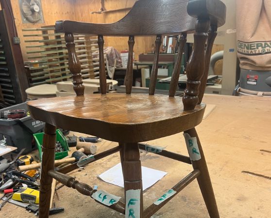 A brown wooden chair with spindle backs and curved armrest before the refinishing