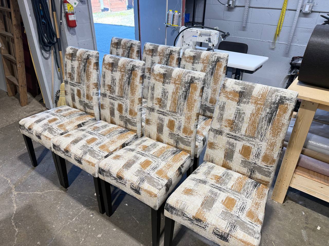 Set of 7 high-back dining chairs with abstract beige, brown, and gray fabric and dark wooden legs.