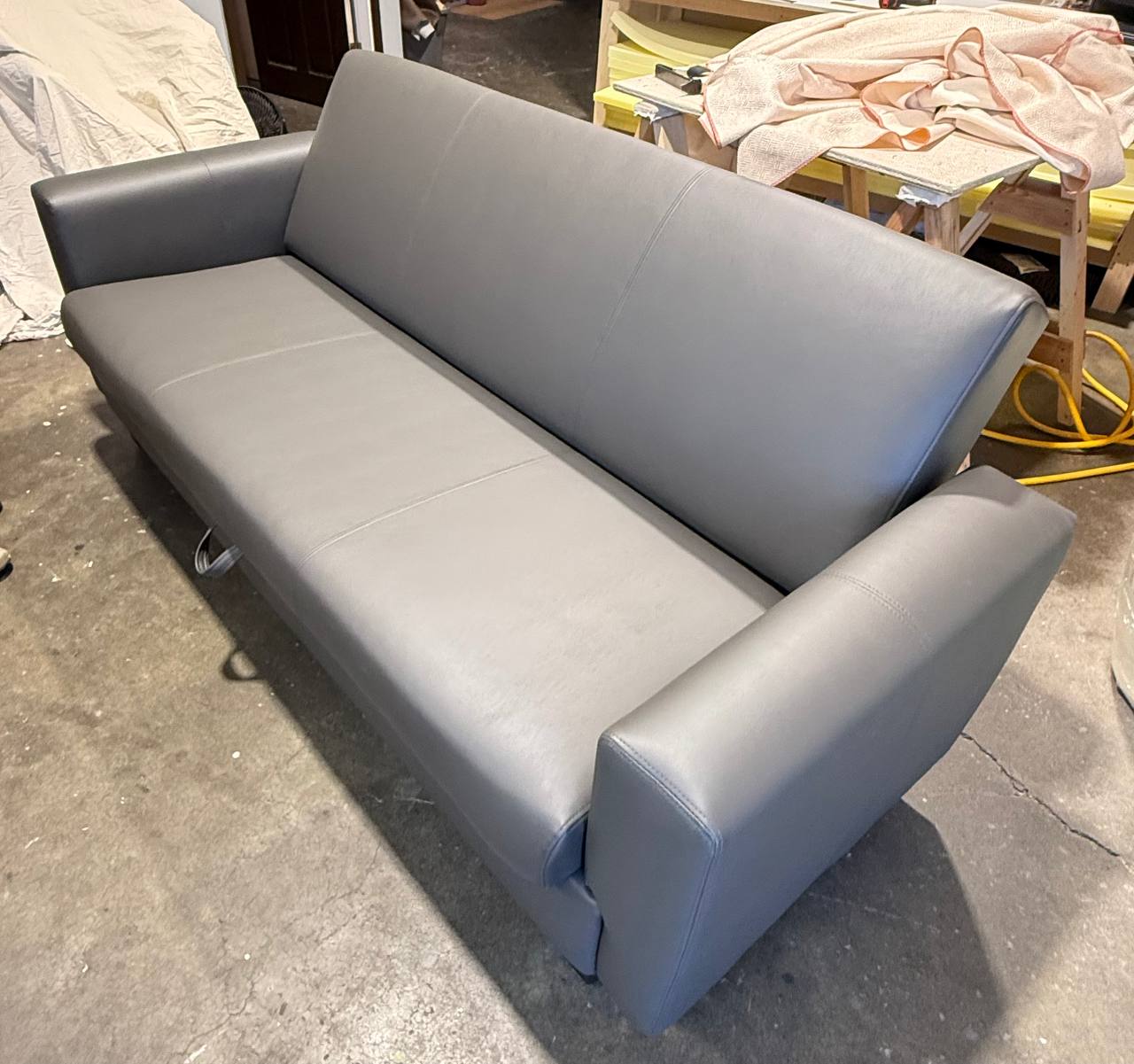 Sleek modern gray leatherette sofa with straight lines and wide arms