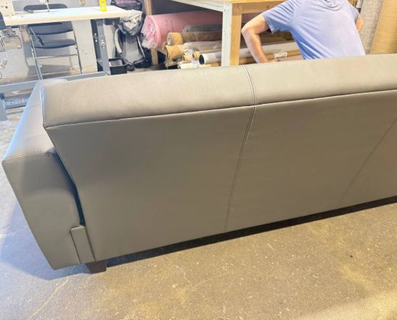 Back of the sleek modern gray vinyl sofa with straight lines and wide arms