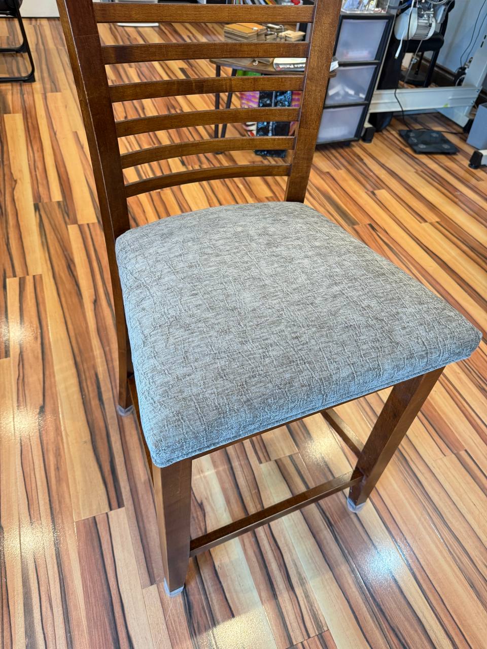 Brown wooden chair with gray cushioned seat, modern slatted design.