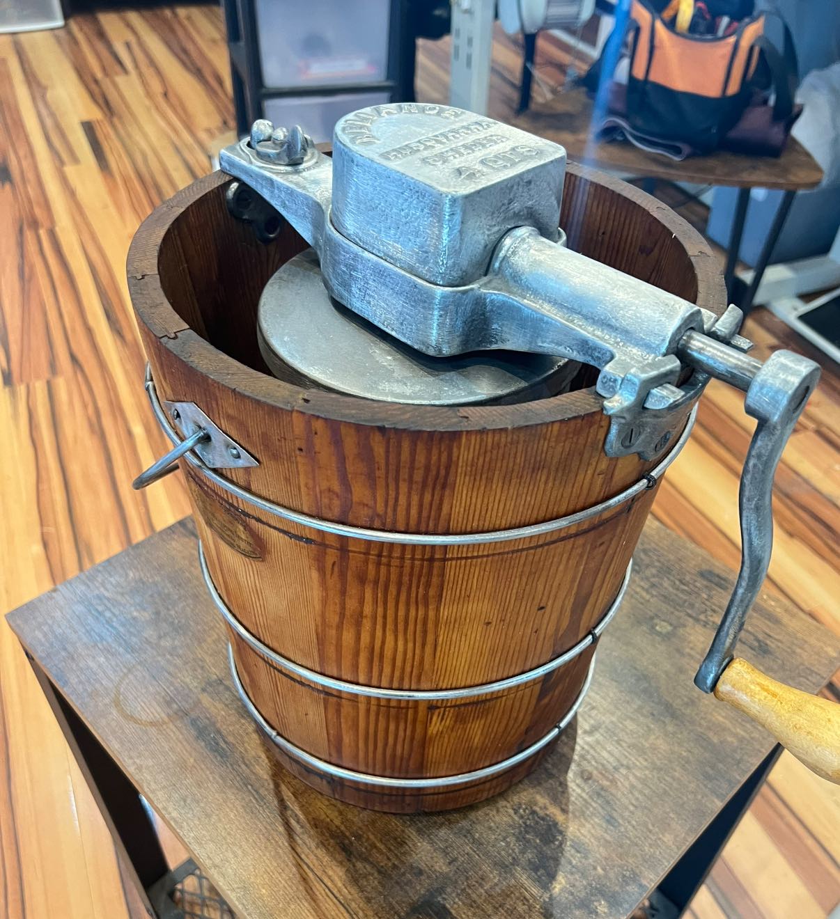 Refinished vintage hand-crank ice cream maker featuring a rustic wood bucket with rich brown grain, silver metal bands, and a cast aluminum crank mechanism.