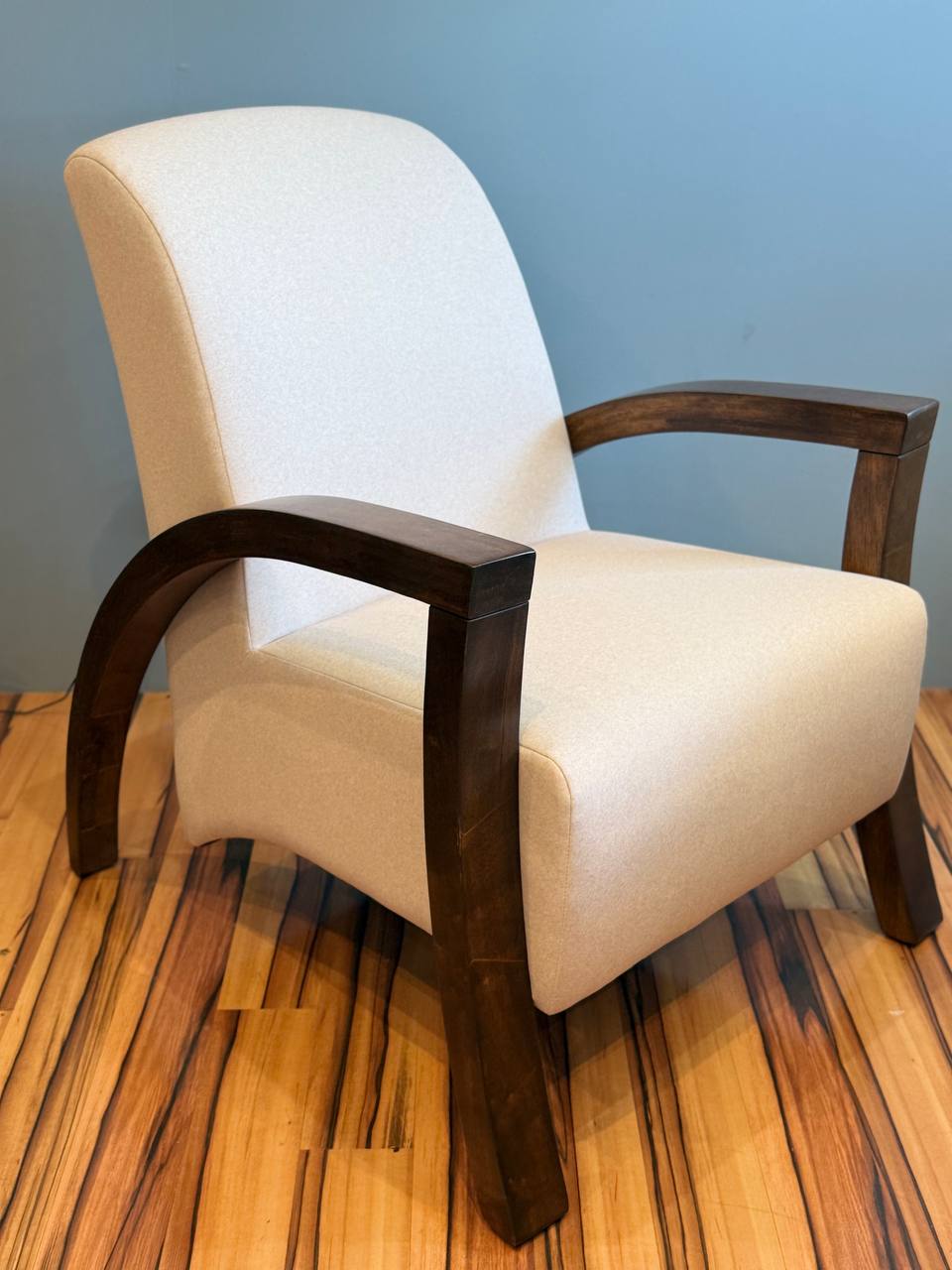 Beige modern armchair with dark wood arms and legs.