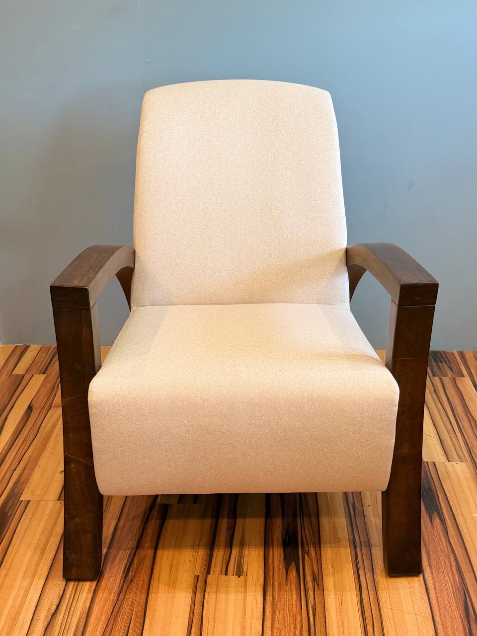Beige modern armchair with dark wood arms and legs.