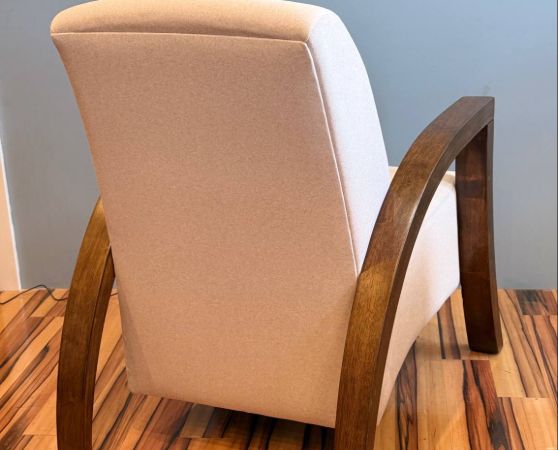 Back of the beige modern armchair with dark wood arms and legs.