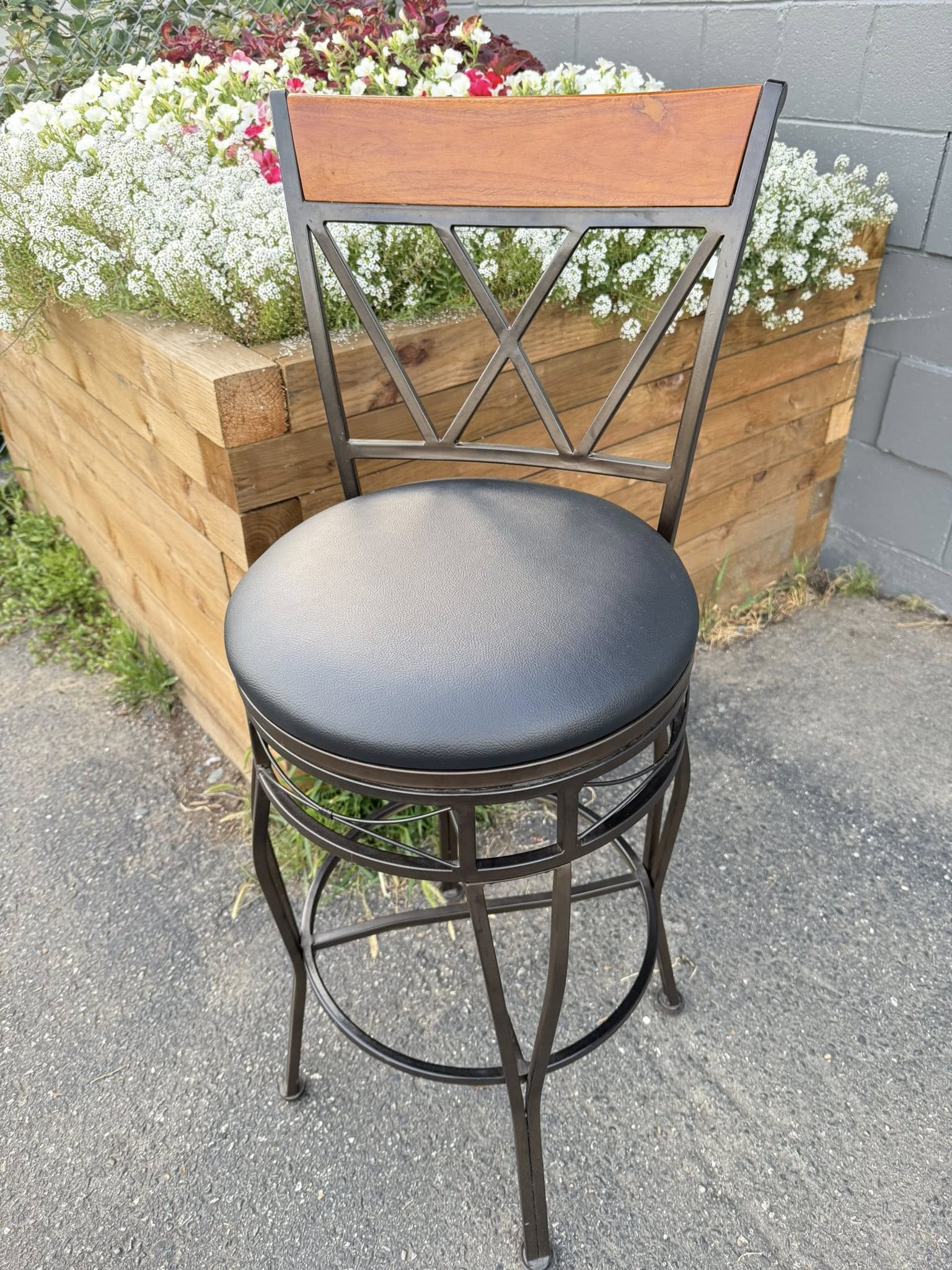 Black metal barstool with gray cushioned seat and wooden backrest