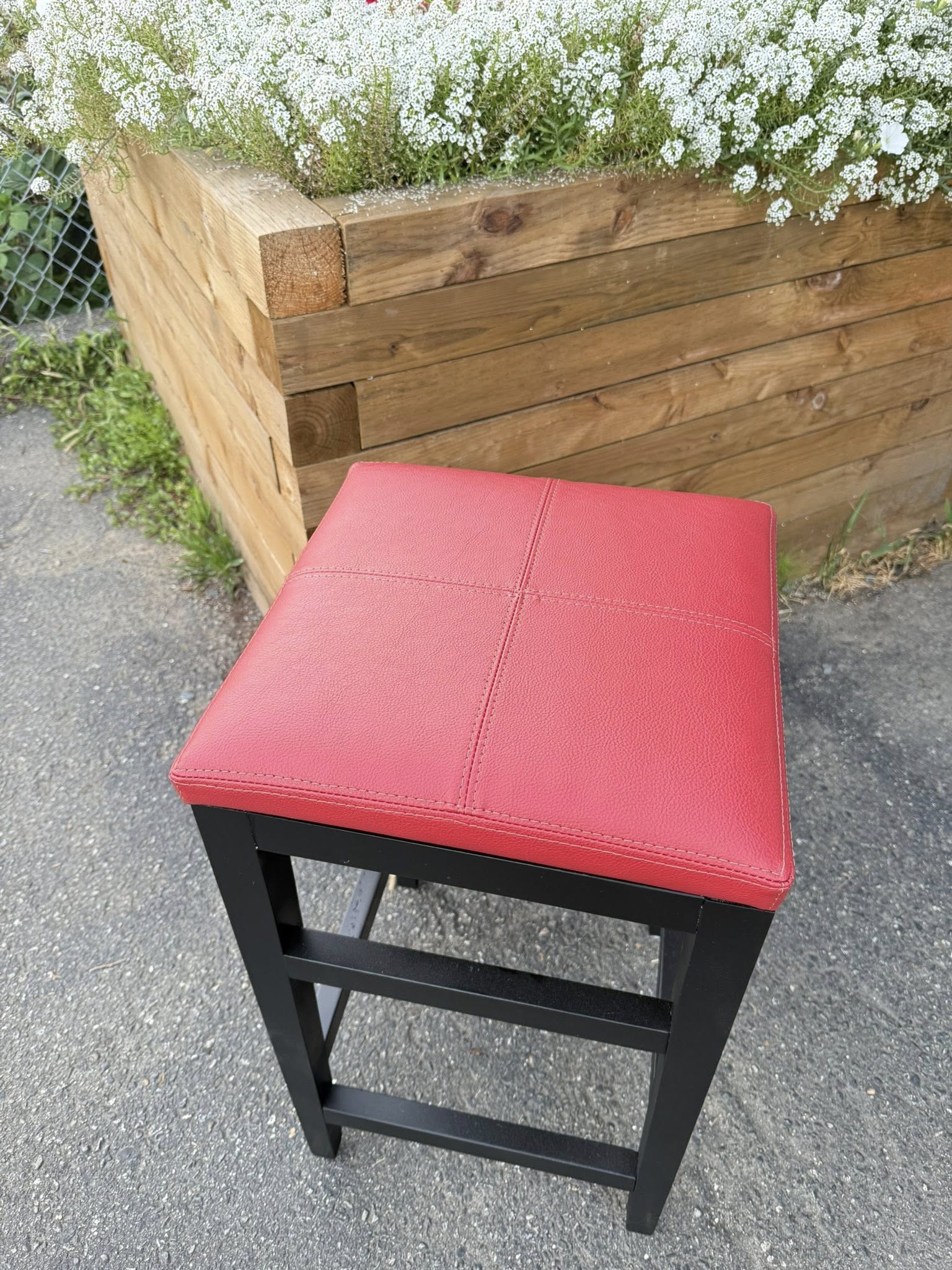 Modern black metal backless barstool with red upholstered seat.