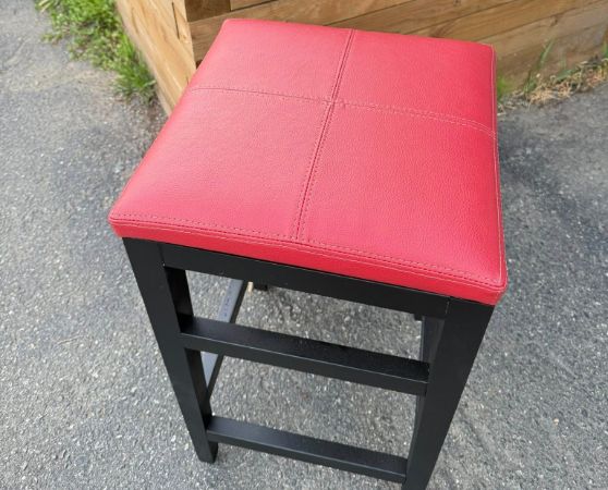 Modern black metal backless barstool with red upholstered seat.