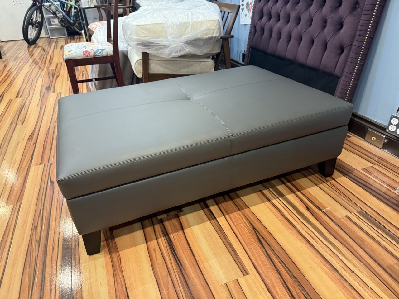 Modern gray storage ottoman, upholstered in sleek fabric with a lift-top design for storage.