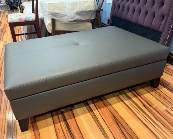 Modern gray storage ottoman, upholstered in sleek fabric with a lift-top design for storage.