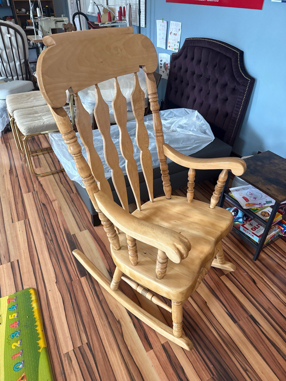 Classic wooden rocking chair with natural finish, featuring an ornate spindle backrest and curved rocking base
