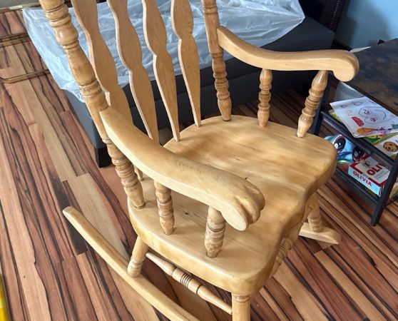 Classic wooden rocking chair with natural finish, featuring an ornate spindle backrest and curved rocking base