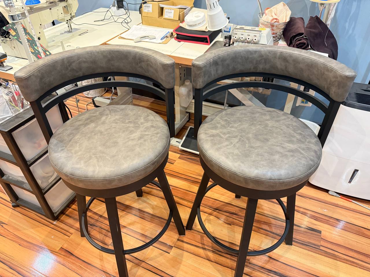 Set of round swivel bar stools with gray leather-look upholstery, black metal base, and curved backrest in a modern contemporary design