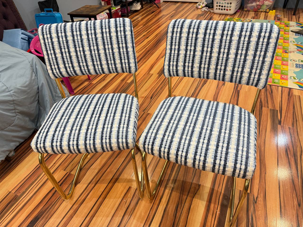 Pair of dining chairs with gold metal legs and blue-and-white striped fabric upholstery in a mid-century modern style