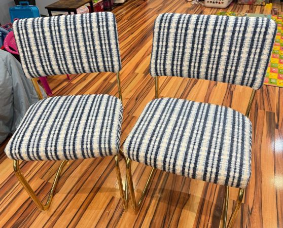 Pair of dining chairs with gold metal legs and blue-and-white striped fabric upholstery in a mid-century modern style