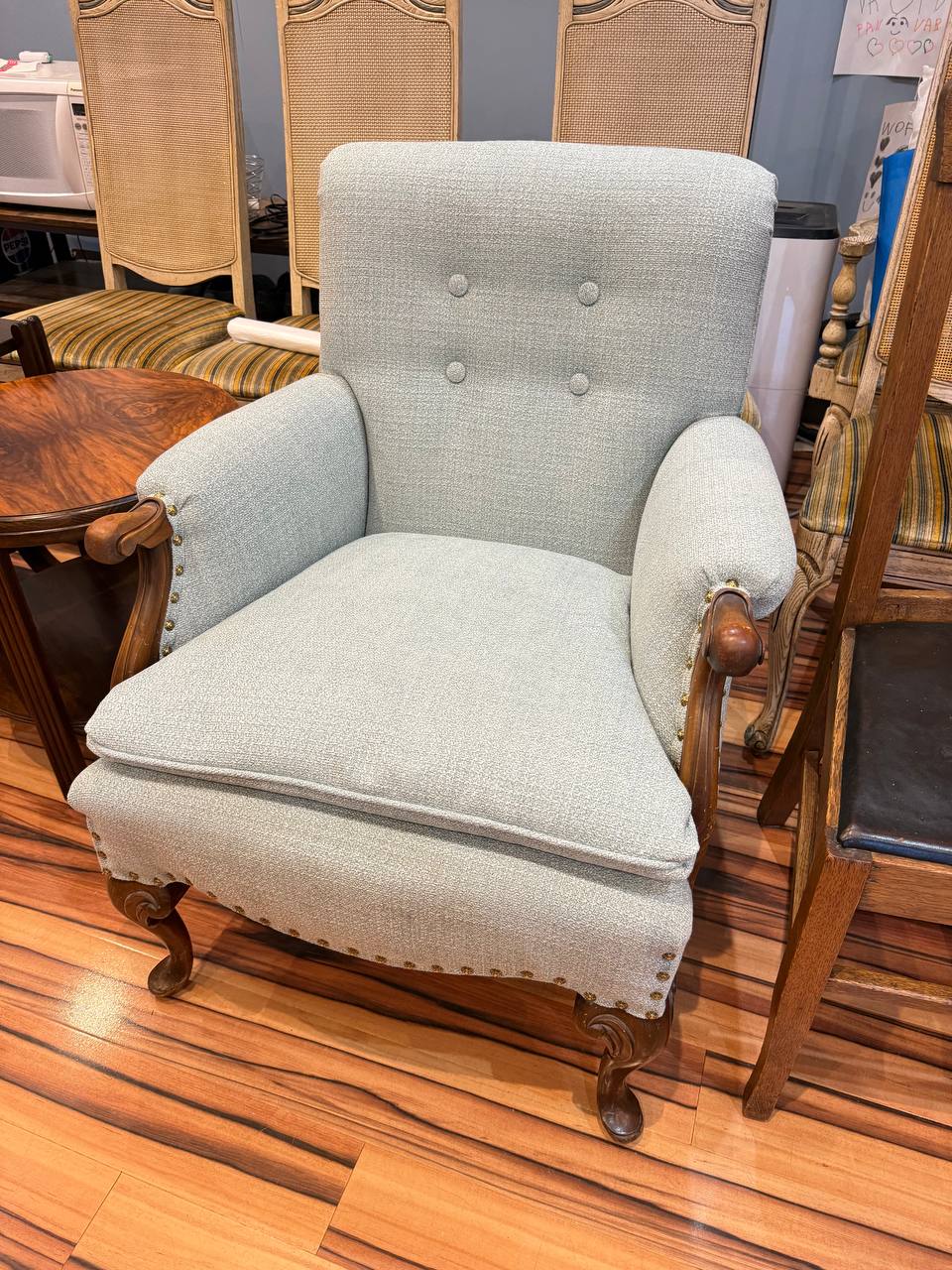 reupholstered antique armchair in light blue fabric with tufted button