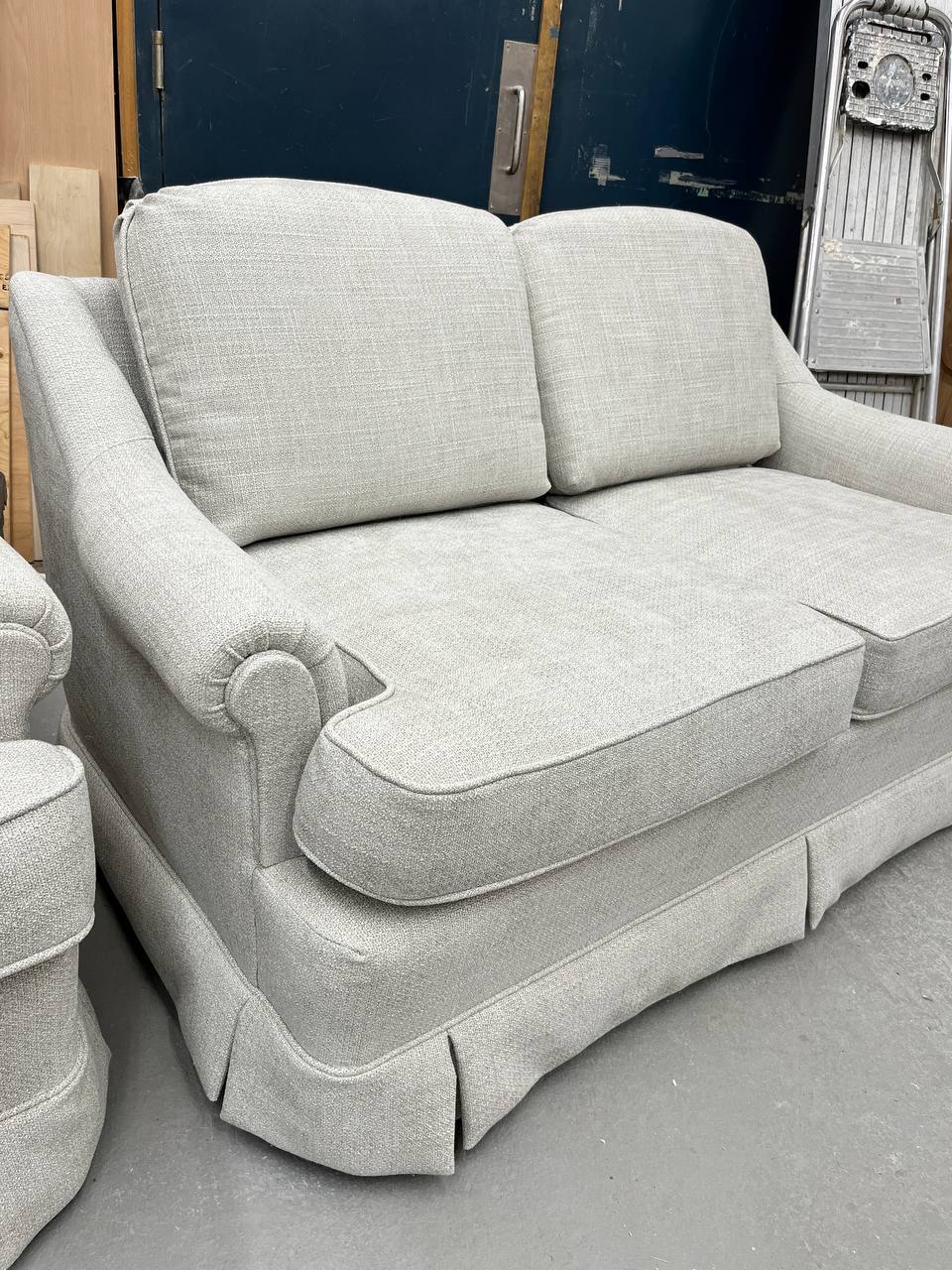 Side view of Reupholstered Loveseat with skirted base and rolled arms in light gray fabric